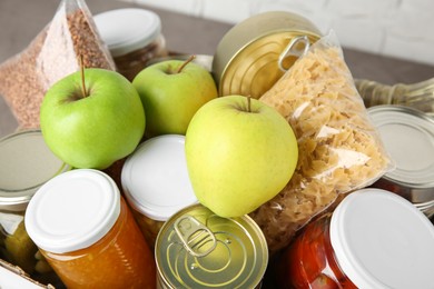 Photo of Different products in box on table, closeup. Food donation