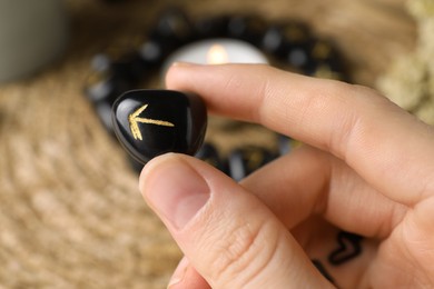 Photo of Woman with black rune Teiwaz at table, closeup