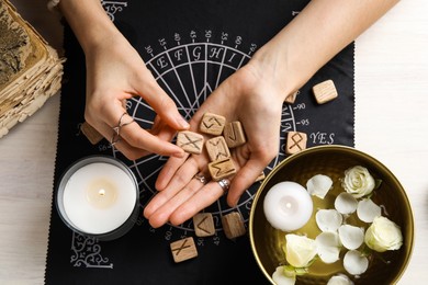 Photo of Woman with wooden runes at table, top view