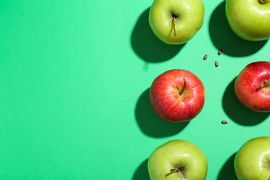 Flat lay composition with different apples and seeds on green background. Space for text