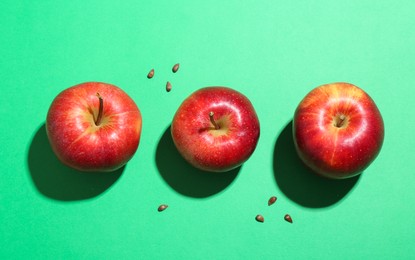 Red apples and seeds on green background, flat lay