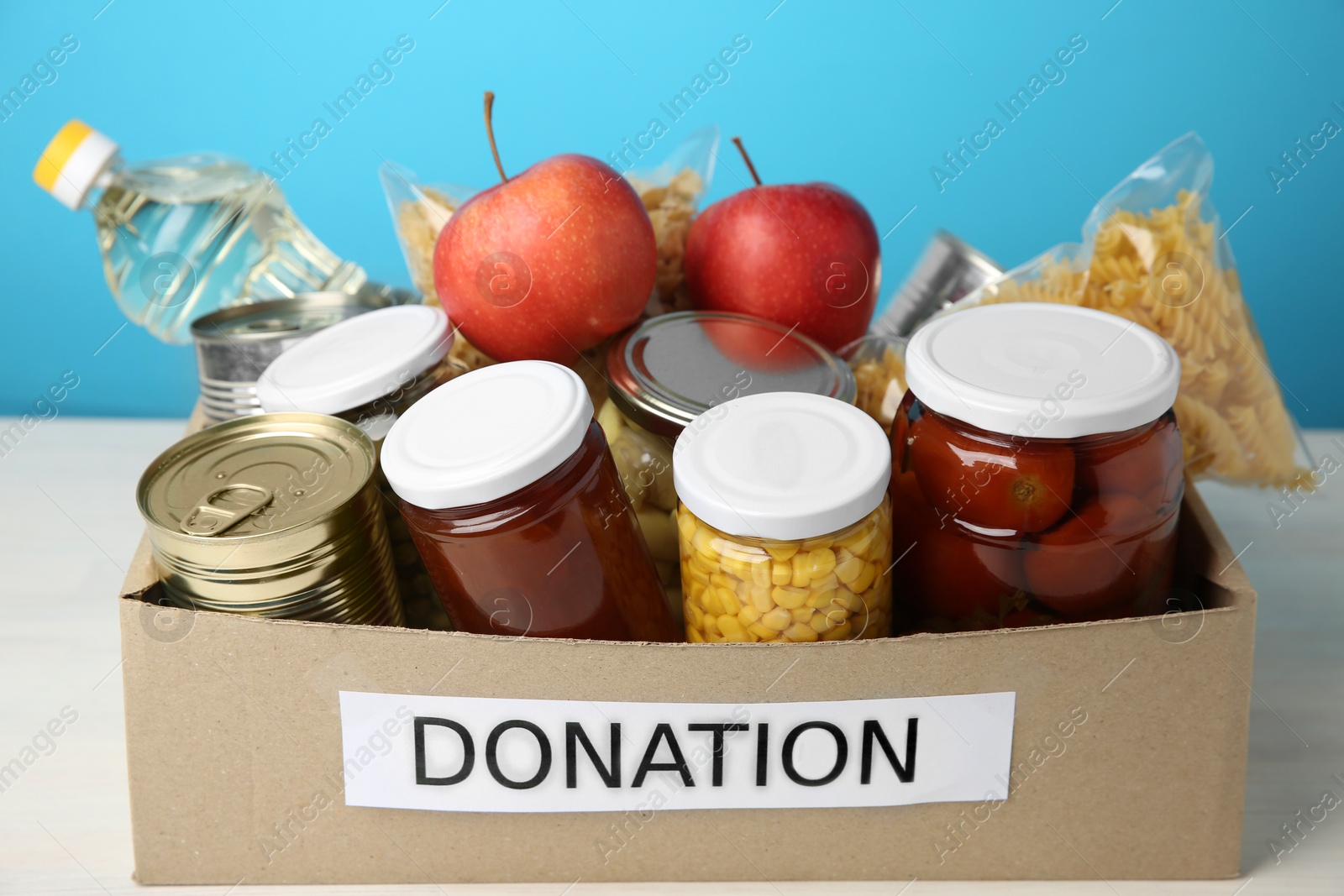 Photo of Different food products for donation in box on table, closeup