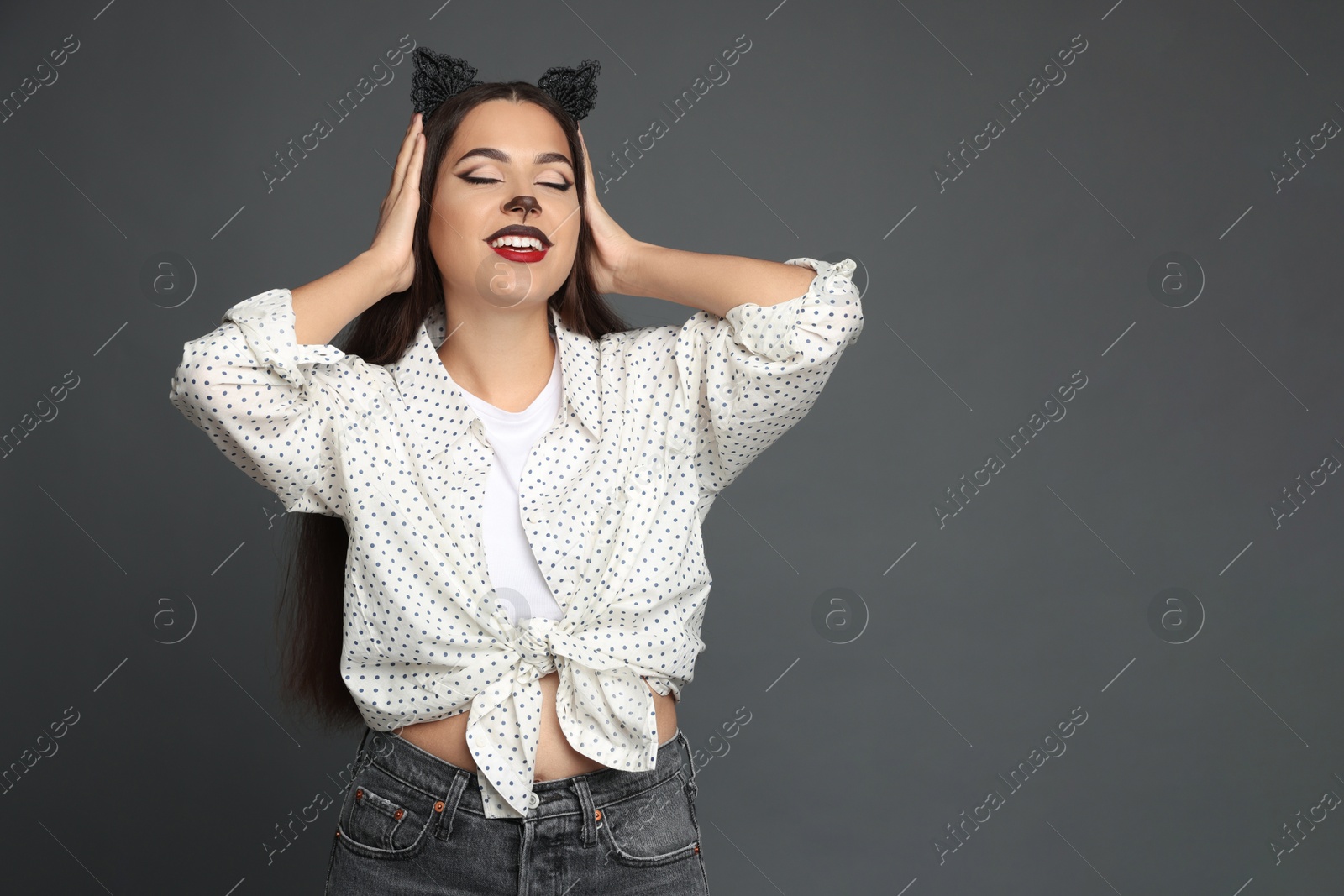 Photo of Attractive woman with cat makeup and ears on grey background. Space for text