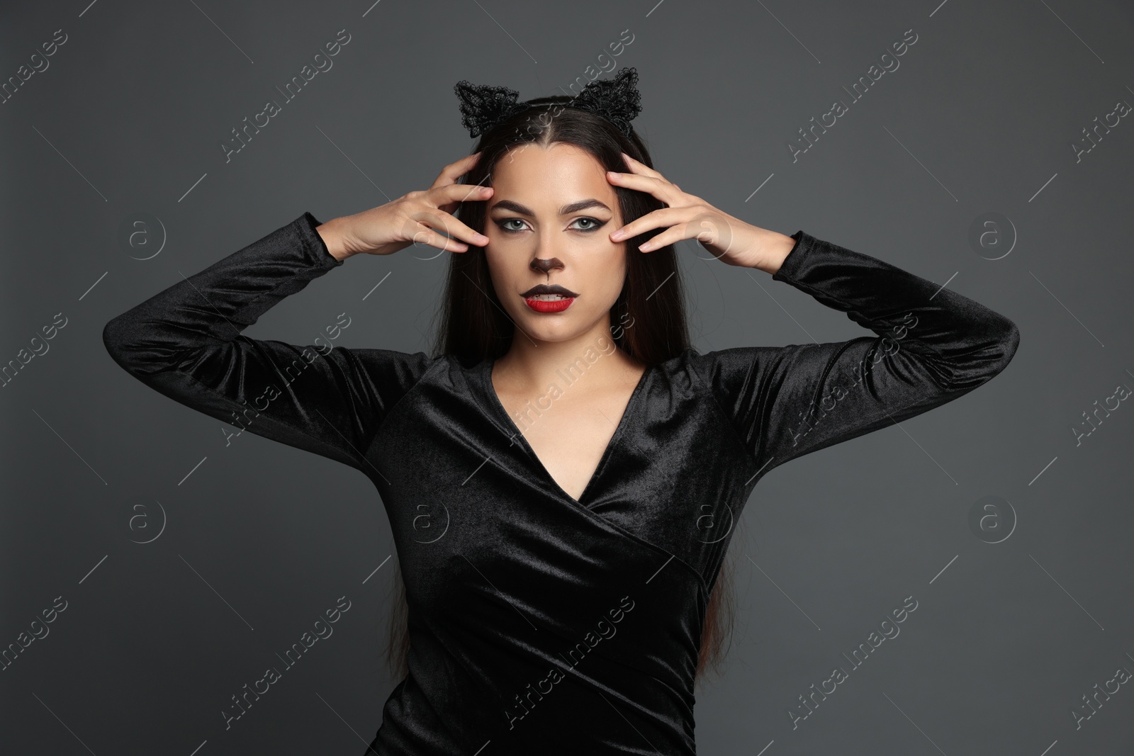 Photo of Attractive woman with cat makeup and ears on grey background