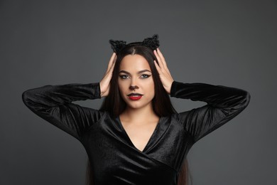 Photo of Attractive woman with cat makeup and ears on grey background