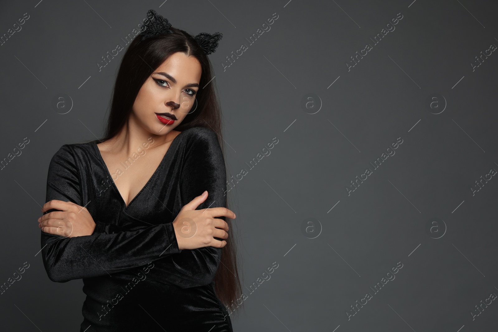 Photo of Attractive woman with cat makeup and ears on grey background. Space for text