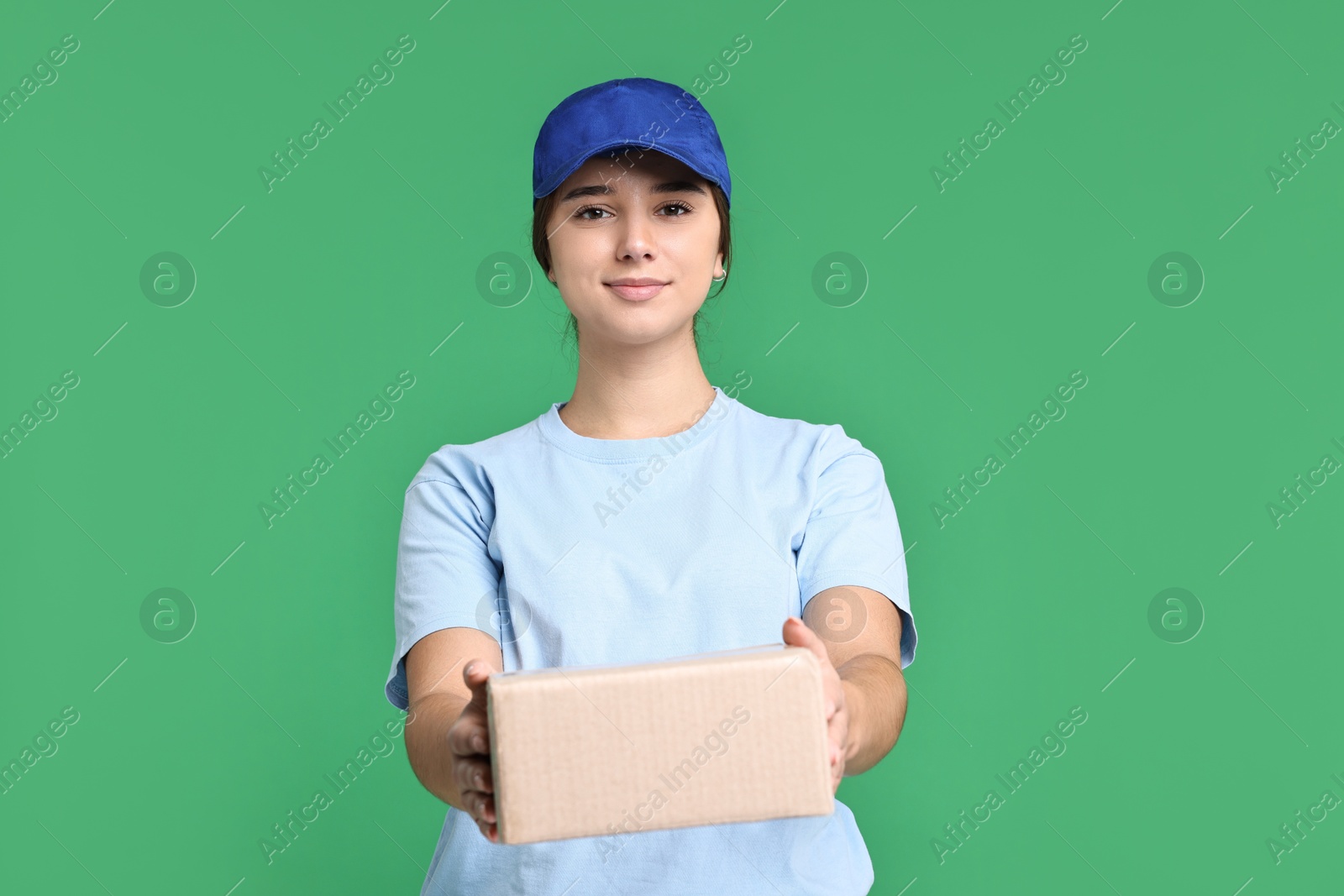 Photo of Girl in uniform with parcel on green background. Work for teenagers