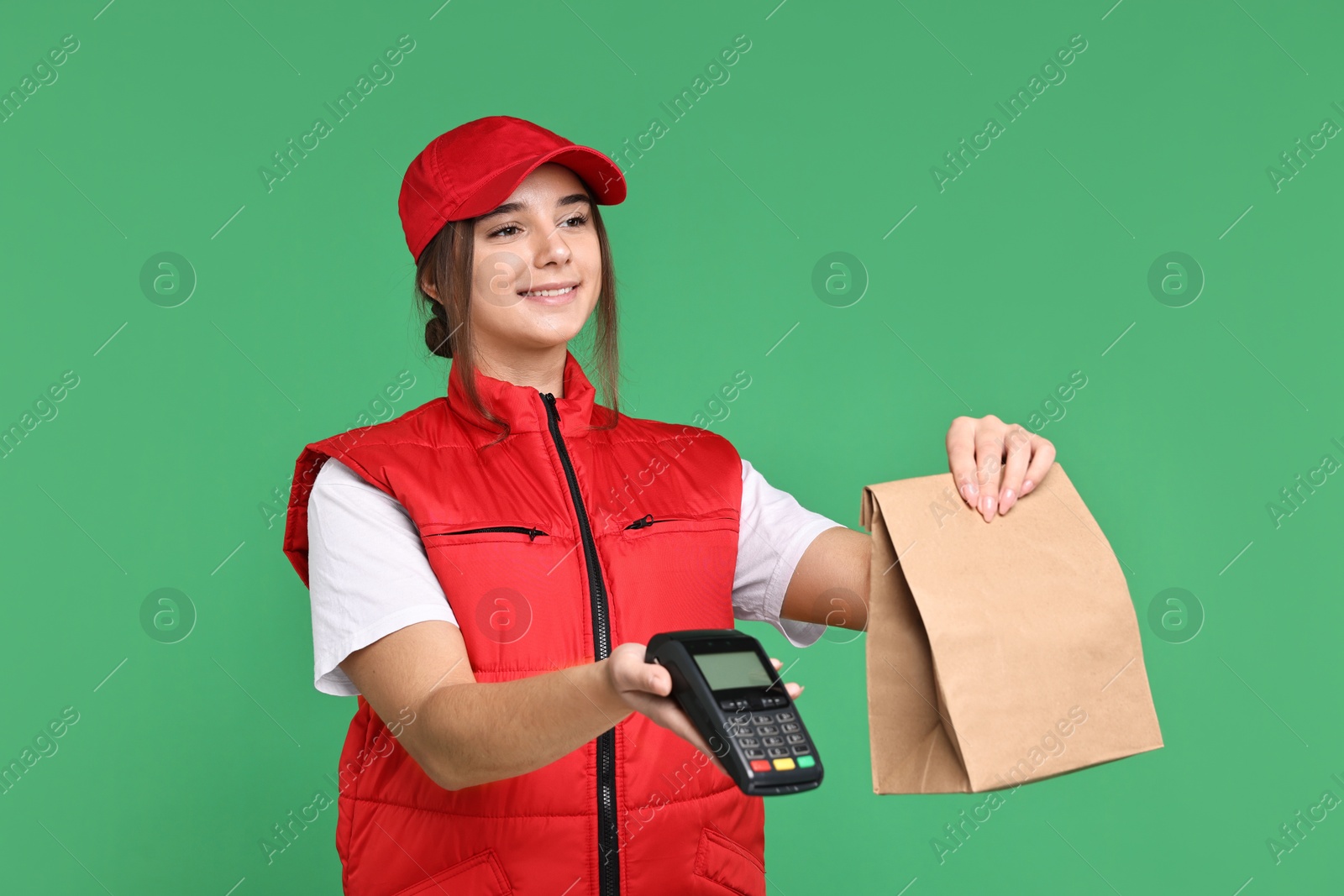 Photo of Girl in uniform with paper bag and payment terminal on green background. Work for teenagers