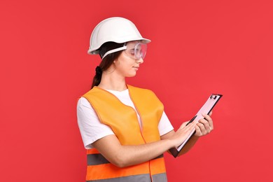 Photo of Girl with safety equipment and clipboard on red background. Work for teenagers