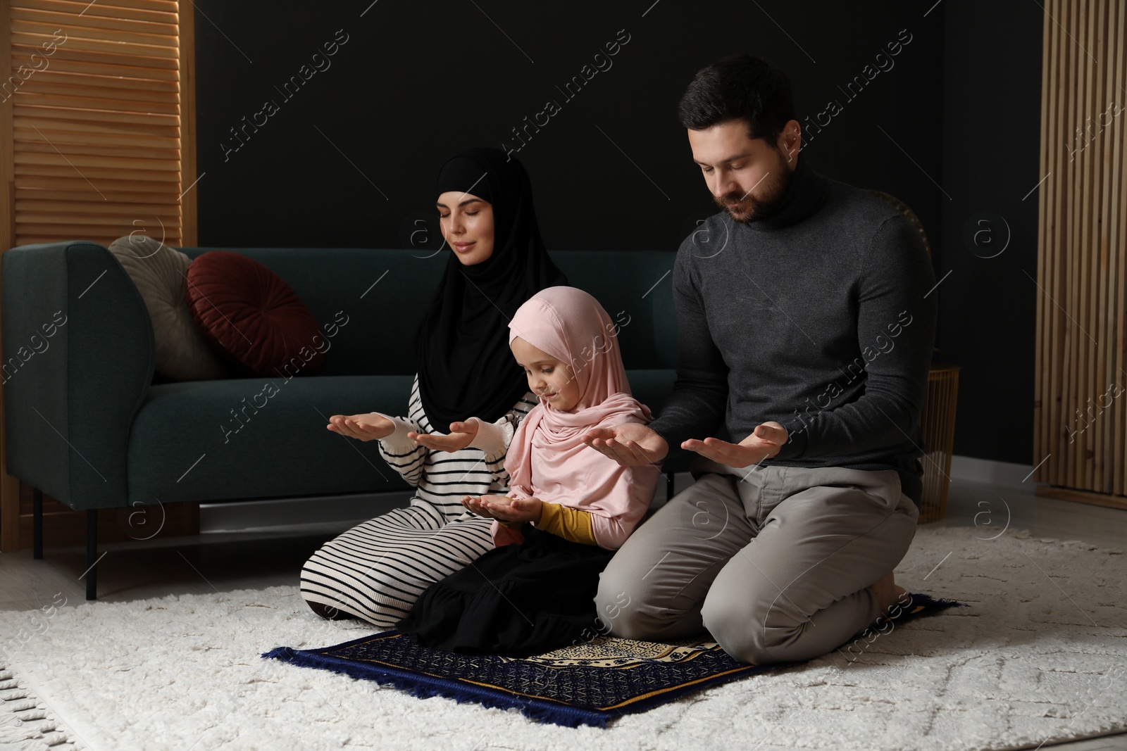 Photo of Muslim family praying on mat at home