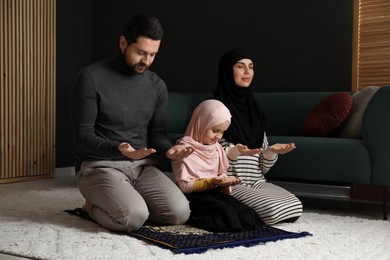 Photo of Muslim family praying on mat at home