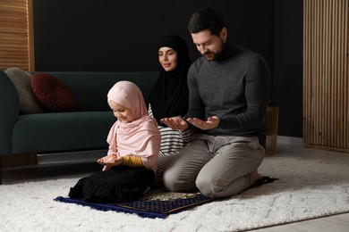 Photo of Muslim family praying on mat at home