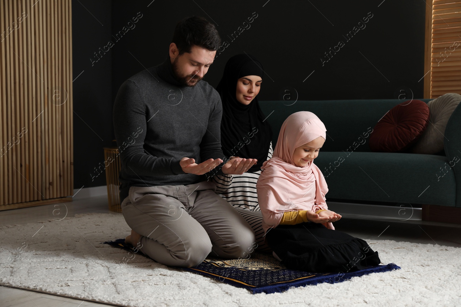 Photo of Muslim family praying on mat at home