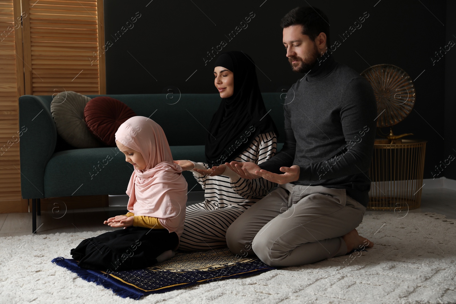 Photo of Muslim family praying on mat at home