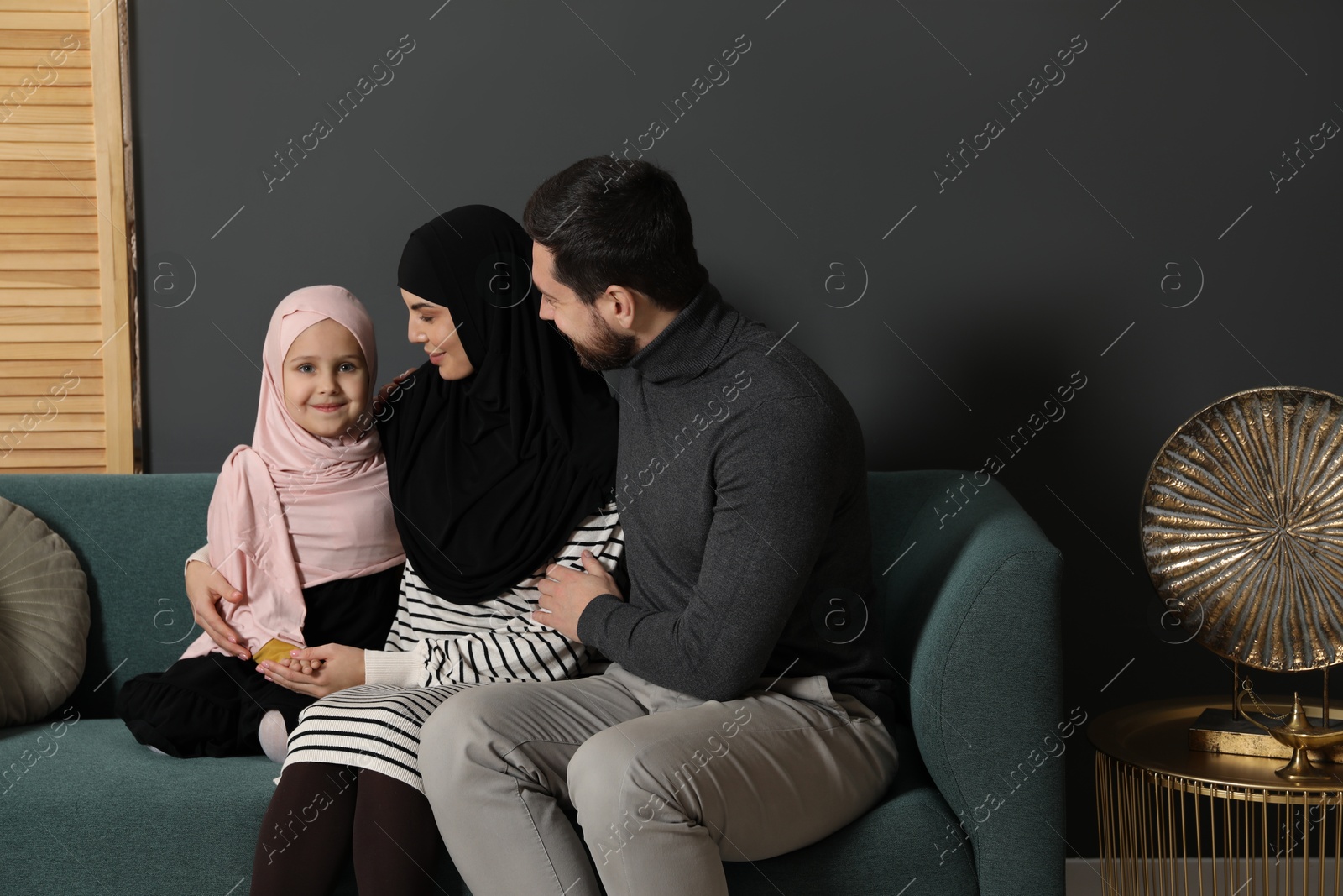 Photo of Happy Muslim family sitting on sofa at home