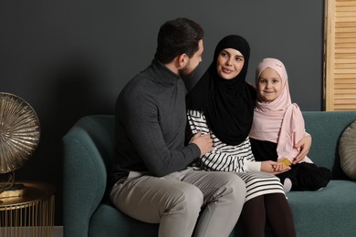 Photo of Happy Muslim family sitting on sofa at home