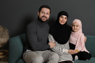 Photo of Happy Muslim family sitting on sofa at home