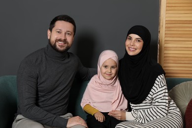 Photo of Happy Muslim family sitting on sofa at home