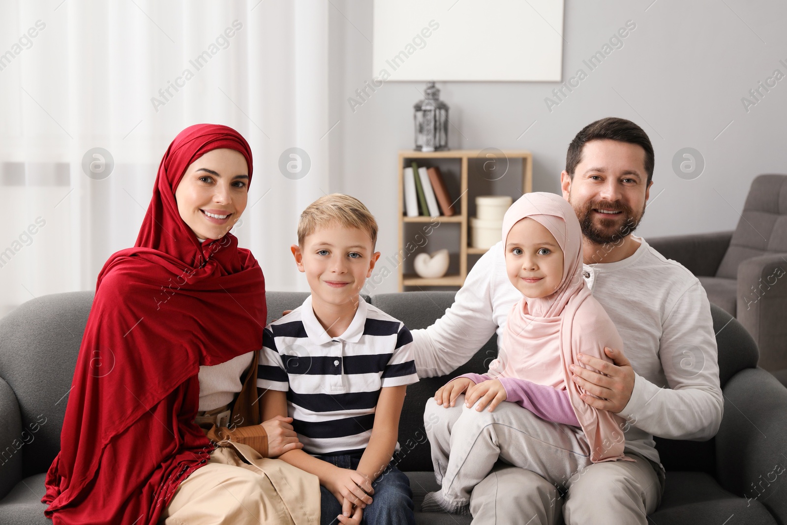 Photo of Happy Muslim family sitting on sofa at home