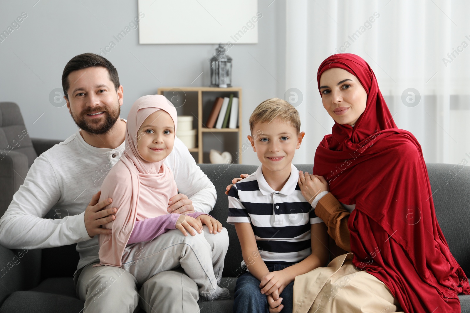 Photo of Happy Muslim family sitting on sofa at home