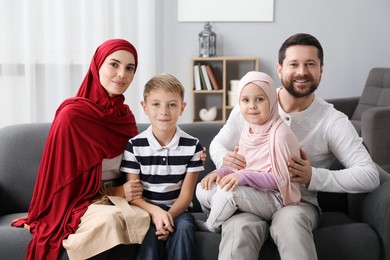 Photo of Happy Muslim family sitting on sofa at home