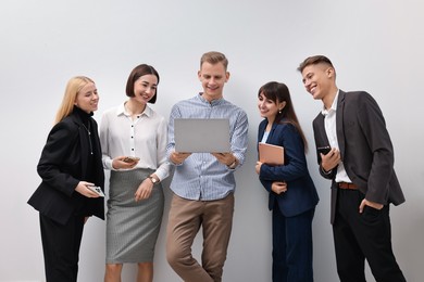 Photo of Group of people using different gadgets near white wall indoors. Modern technology