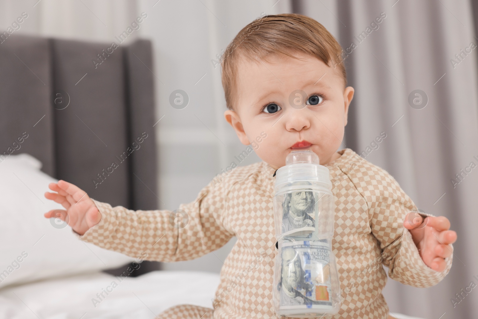 Photo of Cute little baby with money in bottle on bed at home