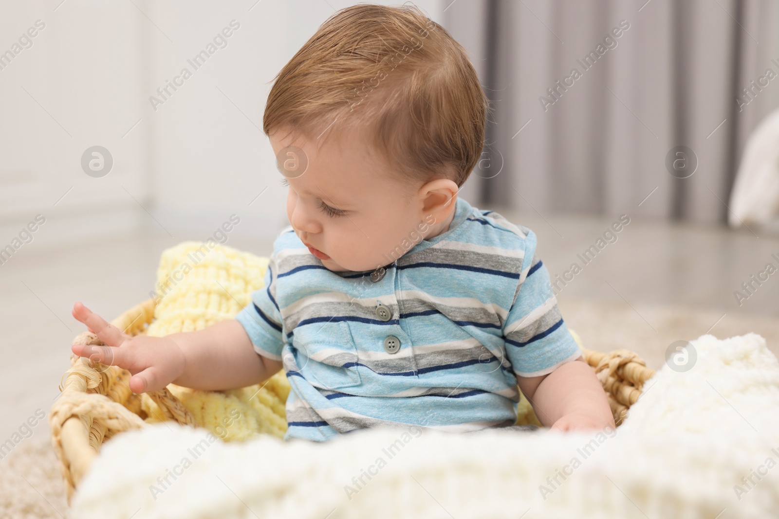 Photo of Cute baby boy in basket at home