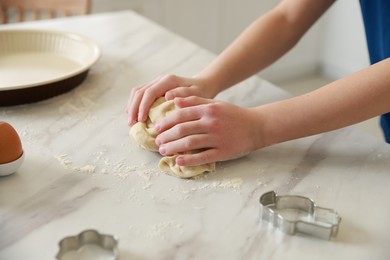 Photo of Boy kneading dough at white marble table in kitchen, closeup