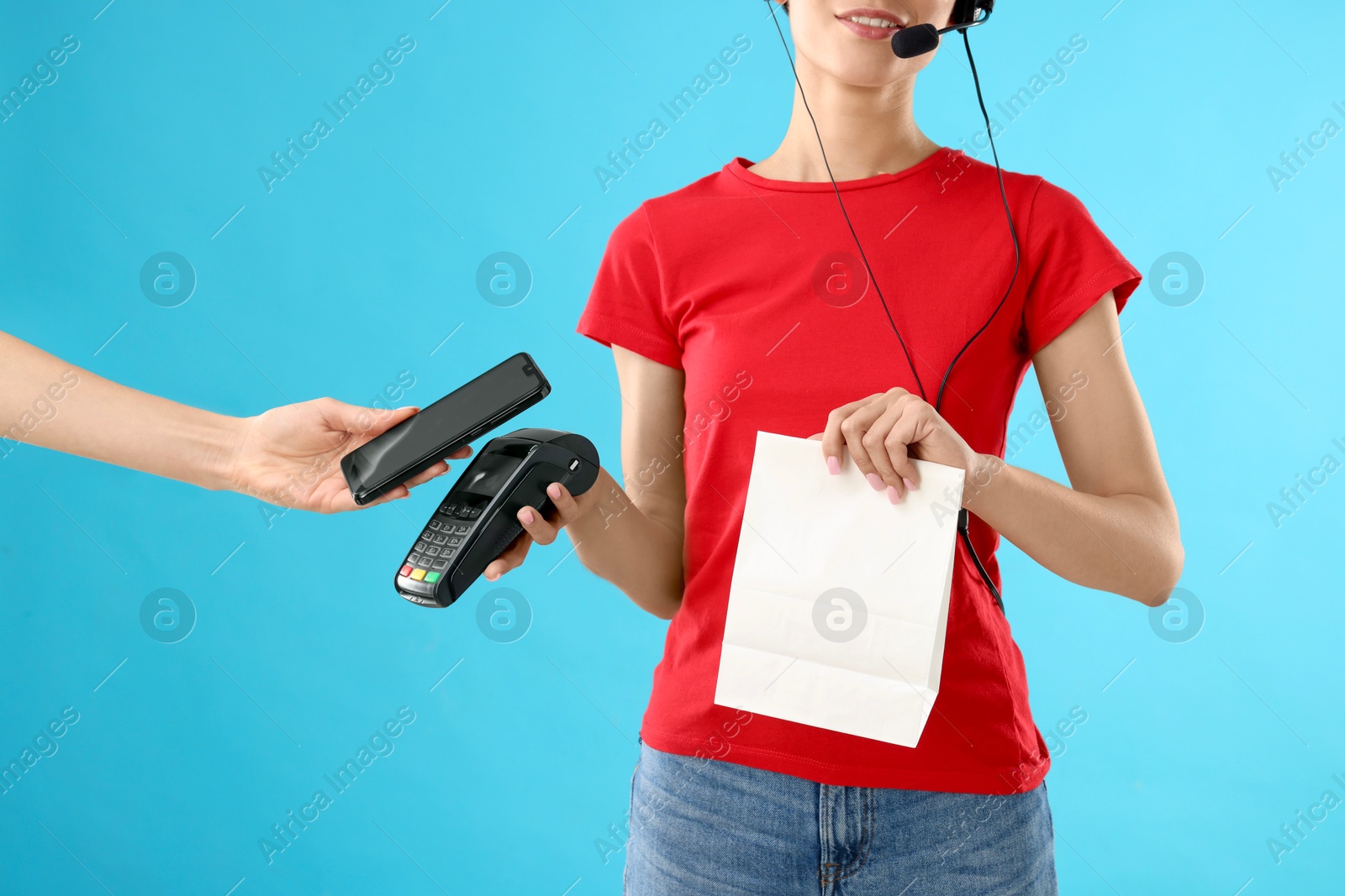 Photo of Fast-food worker taking payment from client via terminal on light blue background, closeup