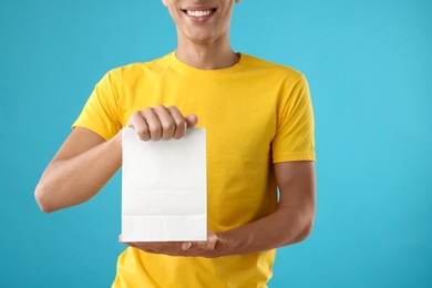 Photo of Fast-food worker with paper bag on light blue background, closeup