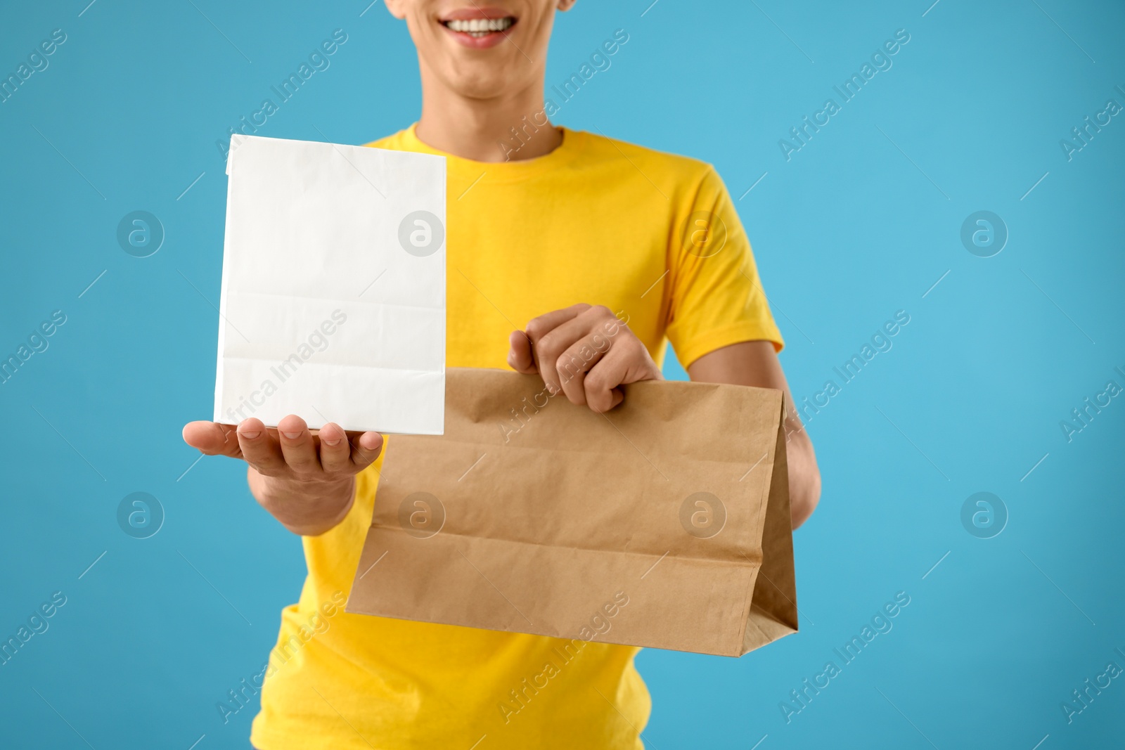 Photo of Fast-food worker with paper bags on light blue background, closeup