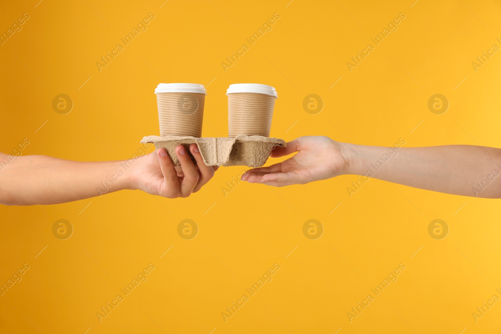 Photo of Fast-food worker giving customer's order on orange background, closeup