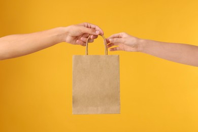 Photo of Fast-food worker giving customer's order on orange background, closeup