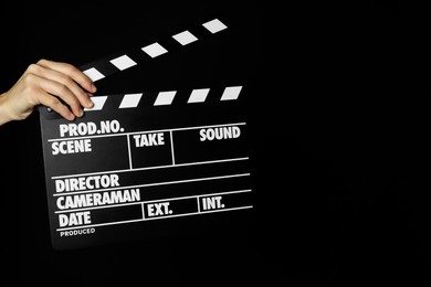 Photo of Woman with clapperboard on black background, closeup. Space for text