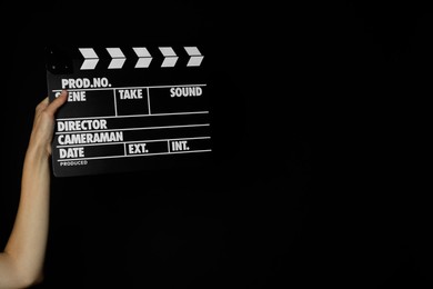 Photo of Woman with clapperboard on black background, closeup. Space for text