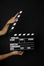 Photo of Woman with clapperboard on black background, closeup