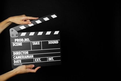 Photo of Woman with clapperboard on black background, closeup. Space for text