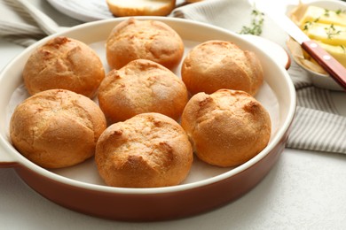 Photo of Baking dish with homemade tasty buns on light table, closeup