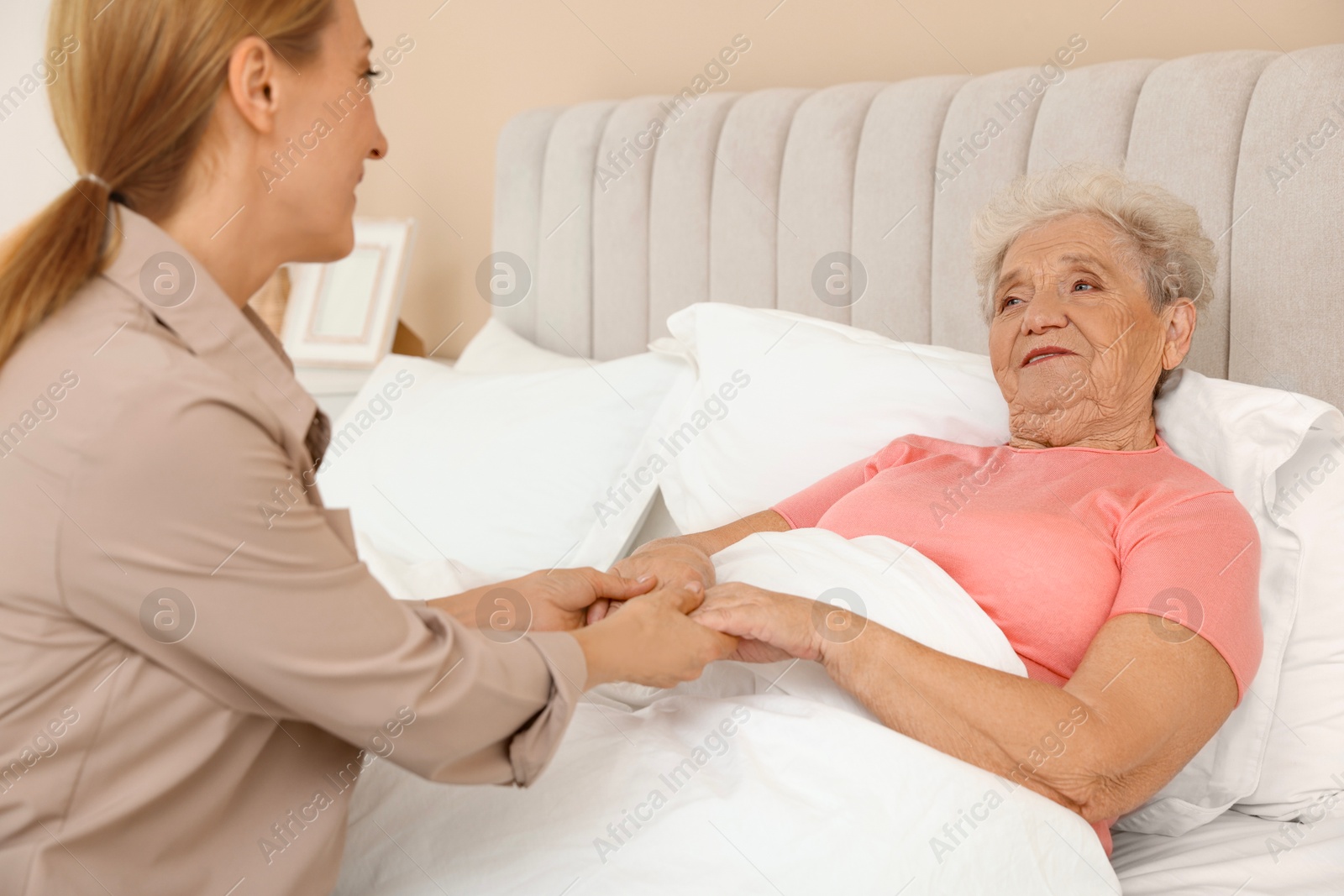 Photo of Caregiver supporting senior patient in bedroom at home