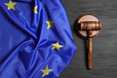 Photo of Judge's gavel and flag of European Union on grey wooden table, top view