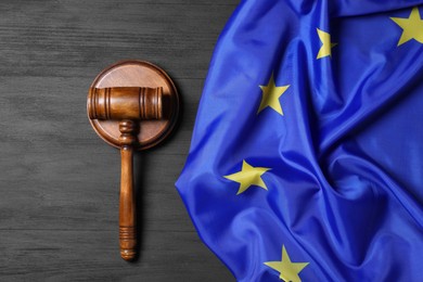 Photo of Judge's gavel and flag of European Union on grey wooden table, top view