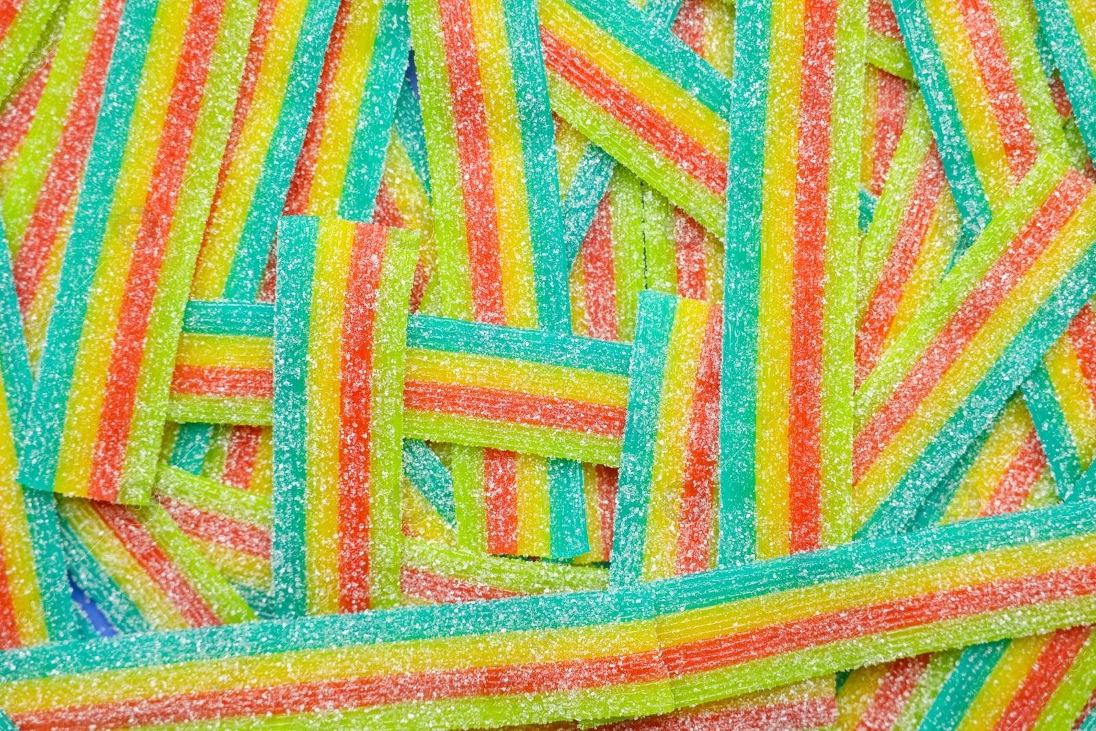 Photo of Tasty rainbow sour belts as background, top view