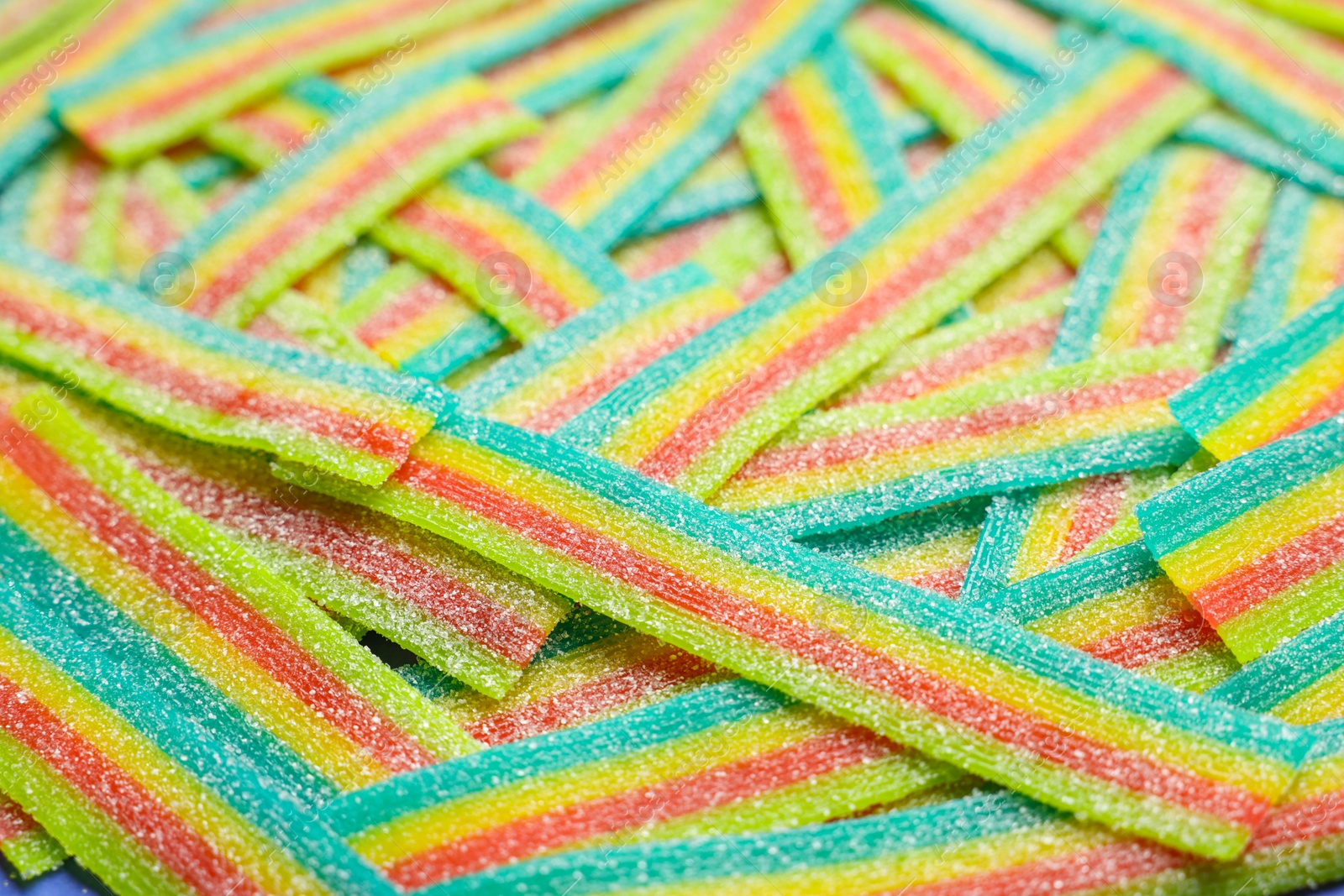 Photo of Tasty rainbow sour belts as background, closeup