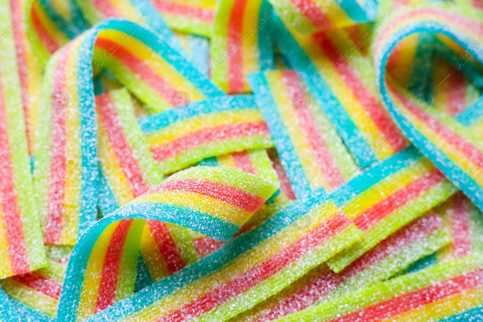 Photo of Tasty rainbow sour belts as background, closeup