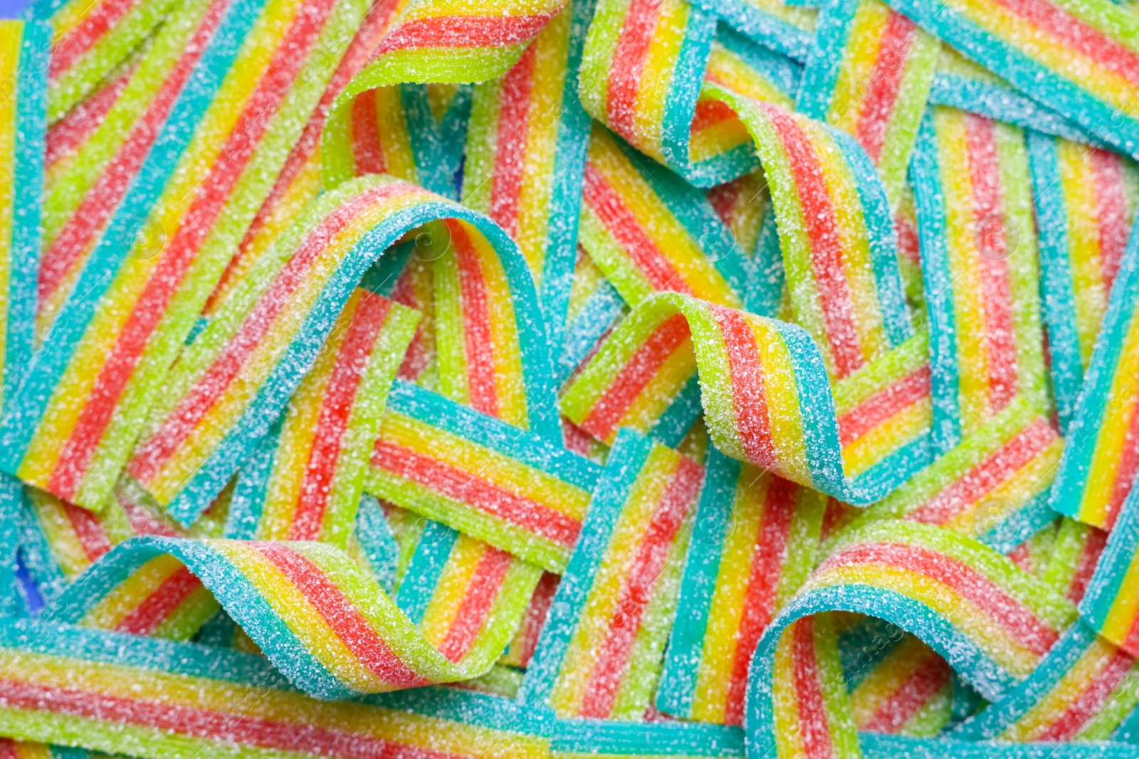 Photo of Tasty rainbow sour belts as background, top view