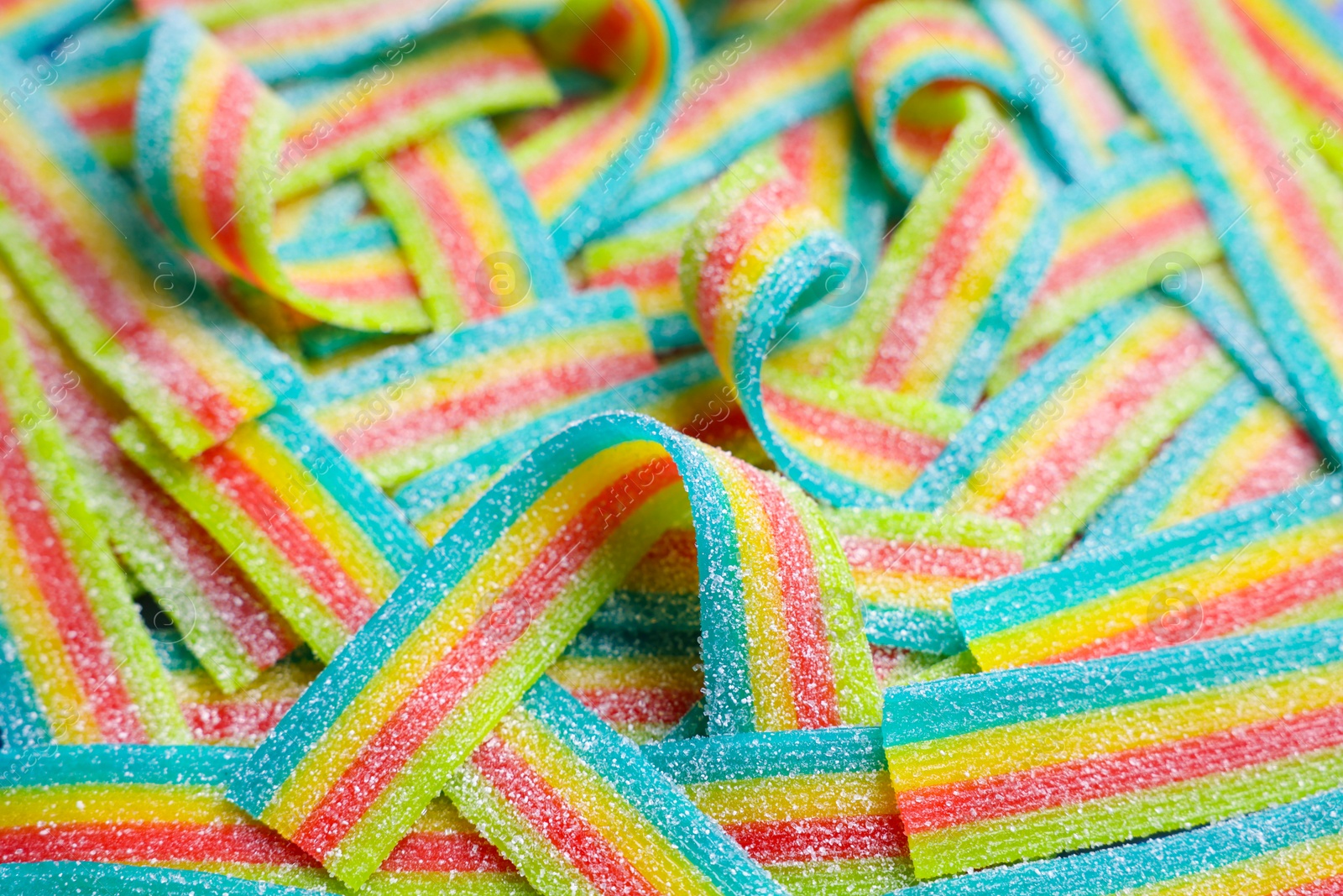 Photo of Tasty rainbow sour belts as background, closeup