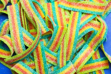 Photo of Tasty rainbow sour belts as background, top view