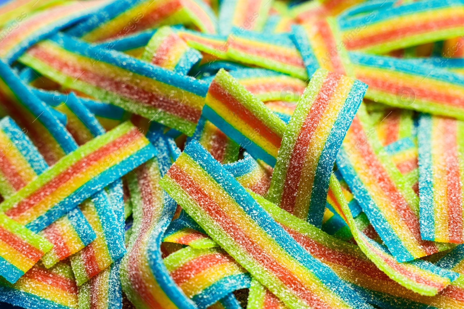 Photo of Tasty rainbow sour belts as background, closeup