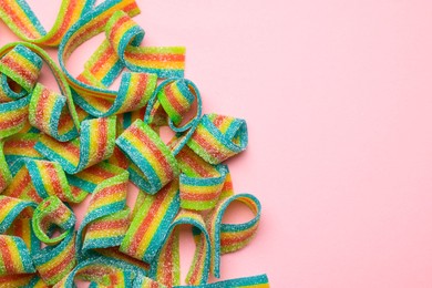 Photo of Tasty rainbow sour belts on pink background, top view. Space for text